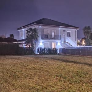 a white house with lights on a yard at night at Villa Petra - Πέτρα in Alpignano