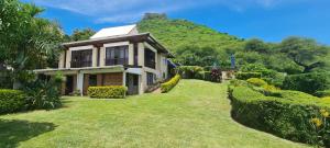una casa con una collina verde sullo sfondo di Flamboyant Ocean View - ex Hillside Haven a Tamarin