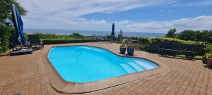 una grande piscina con due persone in piedi accanto di Flamboyant Ocean View - ex Hillside Haven a Tamarin