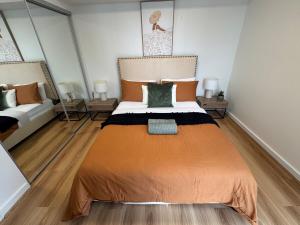 ブリスベンにあるLuxury Apartment Brisbane CBDのベッドルーム1室(大きなオレンジ色のベッド1台、鏡2つ付)