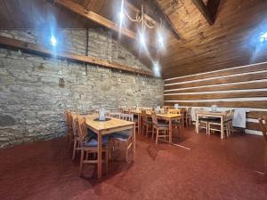 a restaurant with wooden tables and chairs and a stone wall at Restaurace a penzion Na Stráni in Klášterec nad Orlicí