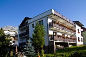 a white building with balconies and flowers on it at Penzión Sibír in Nový Smokovec