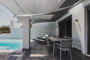 a patio with a table and chairs next to a pool at St Aims by Bluesites in Porto Heli