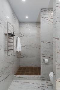 ein Bad mit einer Dusche und weißen Marmorwänden in der Unterkunft Prime City Residence by Sweet Home in Yerevan