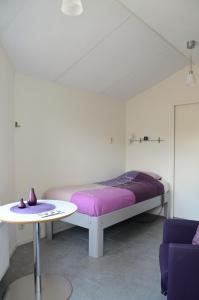 a white room with a bed and a table at Eindhoven 2 Sleep in Eindhoven