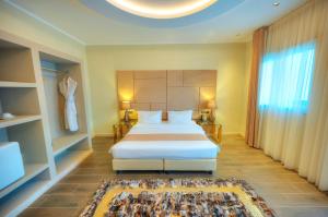 a bedroom with a white bed and a large window at The Segond Hotel in Xagħra