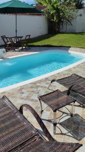une piscine avec deux chaises et un parasol dans l'établissement Casa de Praia em Bertioga, São Paulocom Piscina Ar Condicionado Wifi a 500m do Mar, à Bertioga