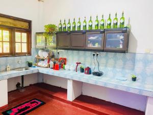a kitchen with a counter with bottles on the wall at Pradeep Guest House Mirissa in Mirissa