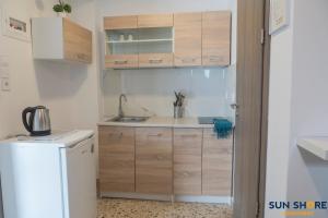 a kitchen with wooden cabinets and a sink and a refrigerator at Explore Greece from Cozy City Centre Apartment in Chalkida