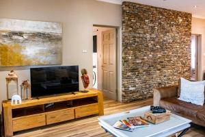 ein Wohnzimmer mit einem TV und einer Ziegelwand in der Unterkunft The Porcupine Porch in Marloth Park