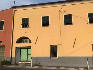 un edificio amarillo con ventanas y una puerta en Ca' du Ventu - Cozy house with mezzanine & little garage, en Calice Ligure