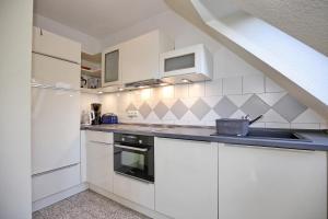 a white kitchen with white cabinets and a sink at Villa Seepferdchen Wohnung 10 in Kühlungsborn +12 photos