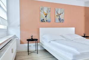 a bedroom with a white bed and three paintings on the wall at Ferienwohnung Schaaf, zentrale Lage, Klimatisiert, Netflix, inklusive Parkplatz in Limburg an der Lahn