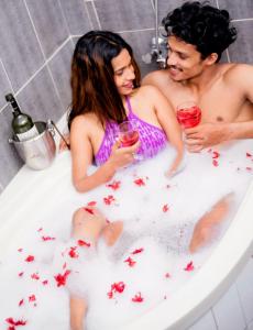 a man and woman sitting in a bath tub with wine glasses at Ayansa Villa Homagama in Homagama