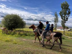 a group of people riding horses in a field at KyzArt Hotel & Horse Tours in Bagysh