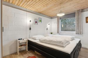 ein Schlafzimmer mit einem großen Bett und einem Fenster in der Unterkunft Feriehus 1102 in Ulfborg