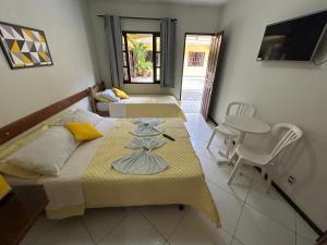 a room with two beds and a table and chairs at Pousada Recanto do Alto de Teresópolis in Teresópolis