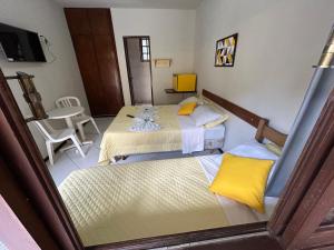 a room with two beds and a table and chairs at Pousada Recanto do Alto de Teresópolis in Teresópolis