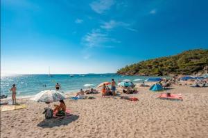 eine Gruppe von Menschen an einem Strand mit Blick auf das Meer in der Unterkunft L'Anse de Pramousquier T2 Vue Mer ! Bord de plage in Le Lavandou