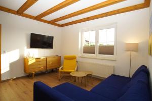 a living room with a blue couch and a yellow chair at Dat Bienenhuus in Putbus