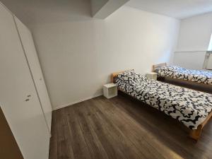 two beds in a small room with wooden floors at Gepflegte Monteurswohnung in Rommerskirchen in Rommerskirchen