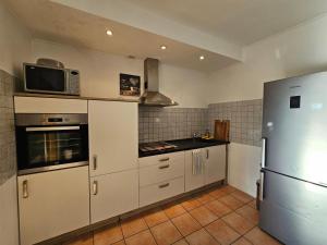 a kitchen with white cabinets and a microwave and a refrigerator at Gepflegte Monteurswohnung in Rommerskirchen in Rommerskirchen