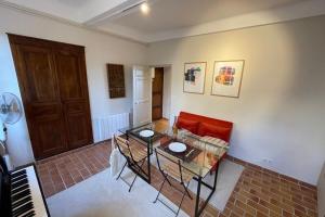 a living room with a red couch and a table and a piano at Charming Studio - in the heart of a medieval village in Bormes-les-Mimosas