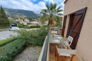 a table and chairs on the balcony of a house at Family apartment - beach access swimming pool in Le Lavandou