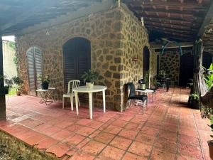 a patio with tables and chairs and a brick wall at Praia do Veloso - Ilha Bela in Ilhabela +2 photos