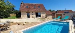 a villa with a swimming pool in front of a house at La petite maison du Ramail in Badefols-dʼAns