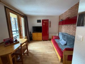a living room with a red couch and a table at Studio au cœur de la station de Risoul 1850 in Risoul