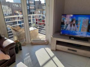 a living room with a flat screen tv and a window at Superbe appartement à koksijde (coxyde) in Koksijde