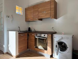 a kitchen with a washing machine and wooden cabinets at Petra House in Porlezza