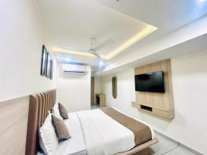 a bedroom with a bed and a flat screen tv at Hotel Shaligram Inn in Ahmedabad