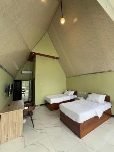 a room with two beds and a tv in it at Kaliningrat Cottage 2 in Pronojiwo