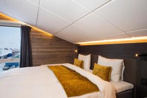 a large bed in a room with a large window at Svalbard Hotell | Lodge in Longyearbyen