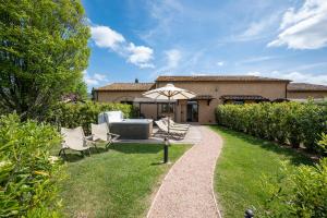 ogród z krzesłami i parasolem przed domem w obiekcie Podere Vignanova Accommodations & SPA w mieście Castagneto Carducci