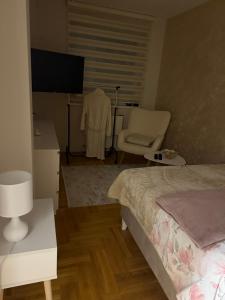 a bedroom with a bed and a chair and a television at Urban Apartman-privatan parking- in Kraljevo