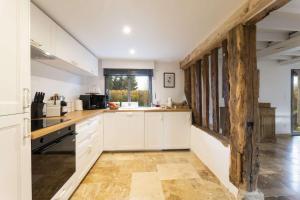 クリックブフにあるMaison Longere Beautiful House near Deauvilleの白いキャビネットと木製の梁があるキッチン