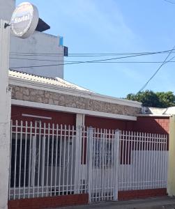 una recinzione bianca di fronte a un edificio rosso di Hostal Amanecer del Valle a Valledupar