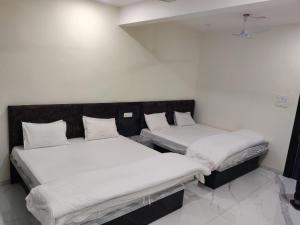 RāipurHotel Anand shree的一间白墙房间里有两张床
