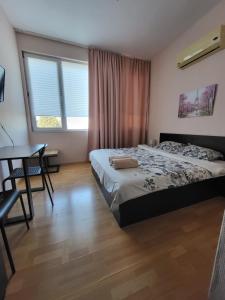 a bedroom with a bed and a desk and window at Стаи за гости Пауза in Stara Zagora