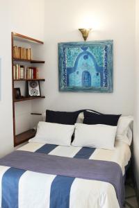 a bedroom with a bed with a blue picture on the wall at Sublime Riad d'artiste au coeur de la médina d'Essaouira in Essaouira