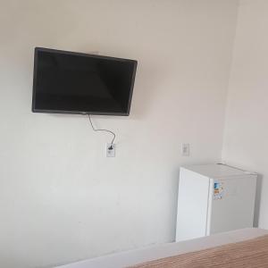 a flat screen tv hanging on a wall next to a refrigerator at Suítes na Beira do mar in Canavieiras +7 photos