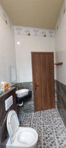 a bathroom with a toilet and a wooden door at Home Coffee shop Tỷ Uyên in Phu Quoc