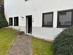 a white house with black windows and a walkway at Modernes ruhiges Apartment in Scheidt, Uni-Nähe in Saarbrücken