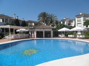 ein großer blauer Swimmingpool mit Stühlen und Sonnenschirmen in der Unterkunft Hacienda Beach in Estepona
