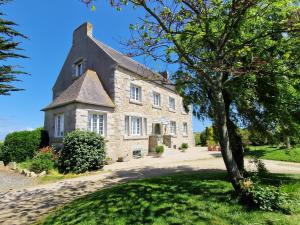 an old stone house with a tree in front of it at Entre Terre et Mer in Plougoulm