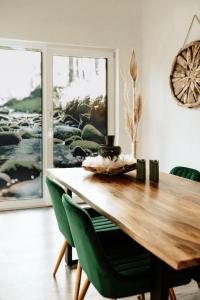 une salle à manger avec une table en bois et des chaises vertes dans l'établissement Waldzauber Appartement, à Horhausen