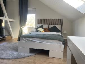 a white bedroom with a bed with pillows and a window at Gemütliches Mansarden-Apartment mit 2 Schlafzimmern & separater Küche in Herne